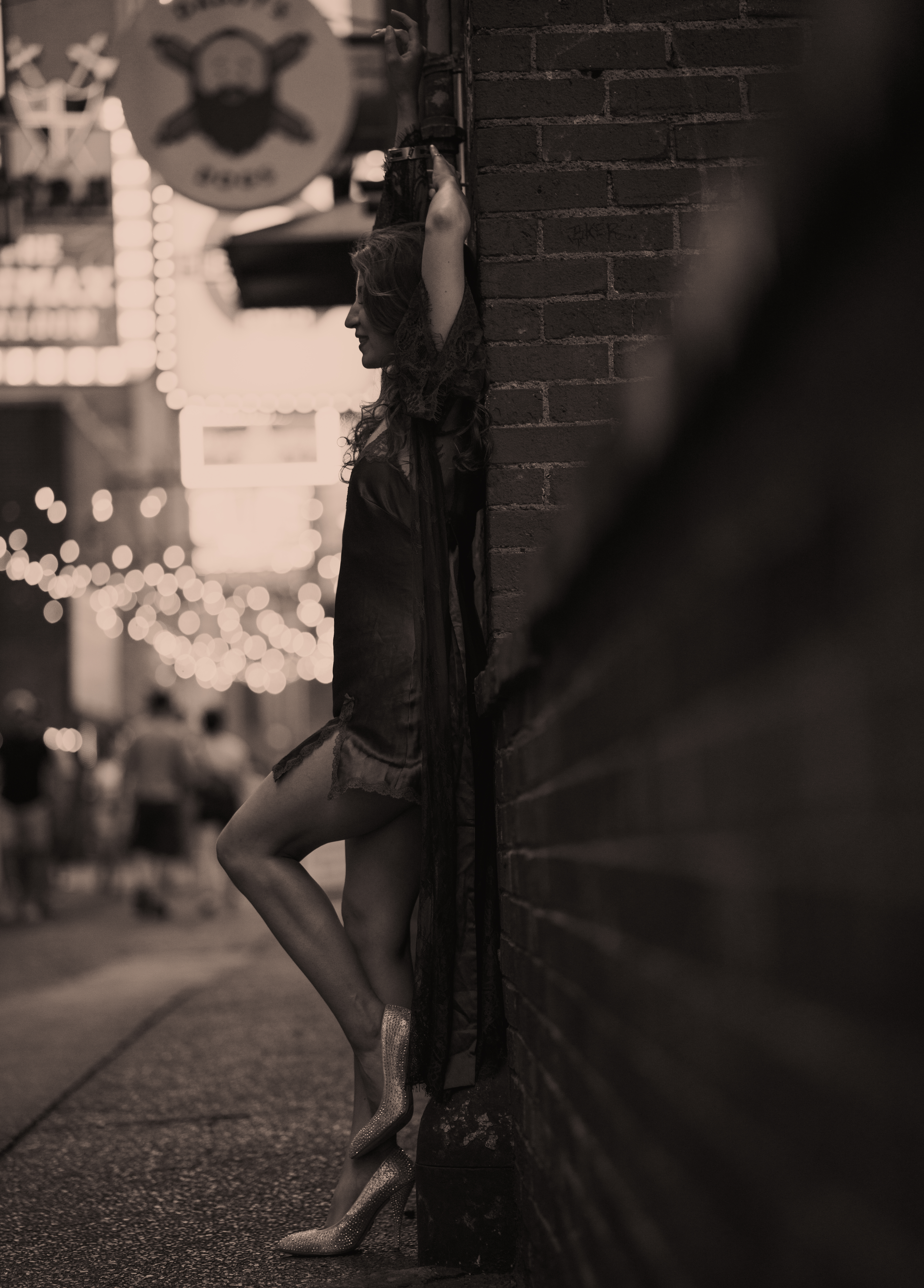 Nashville Tennessee Jazz Musician poses in Printer's Alley at night for album cover. She leans back against a brick wall with her shoe propped up.