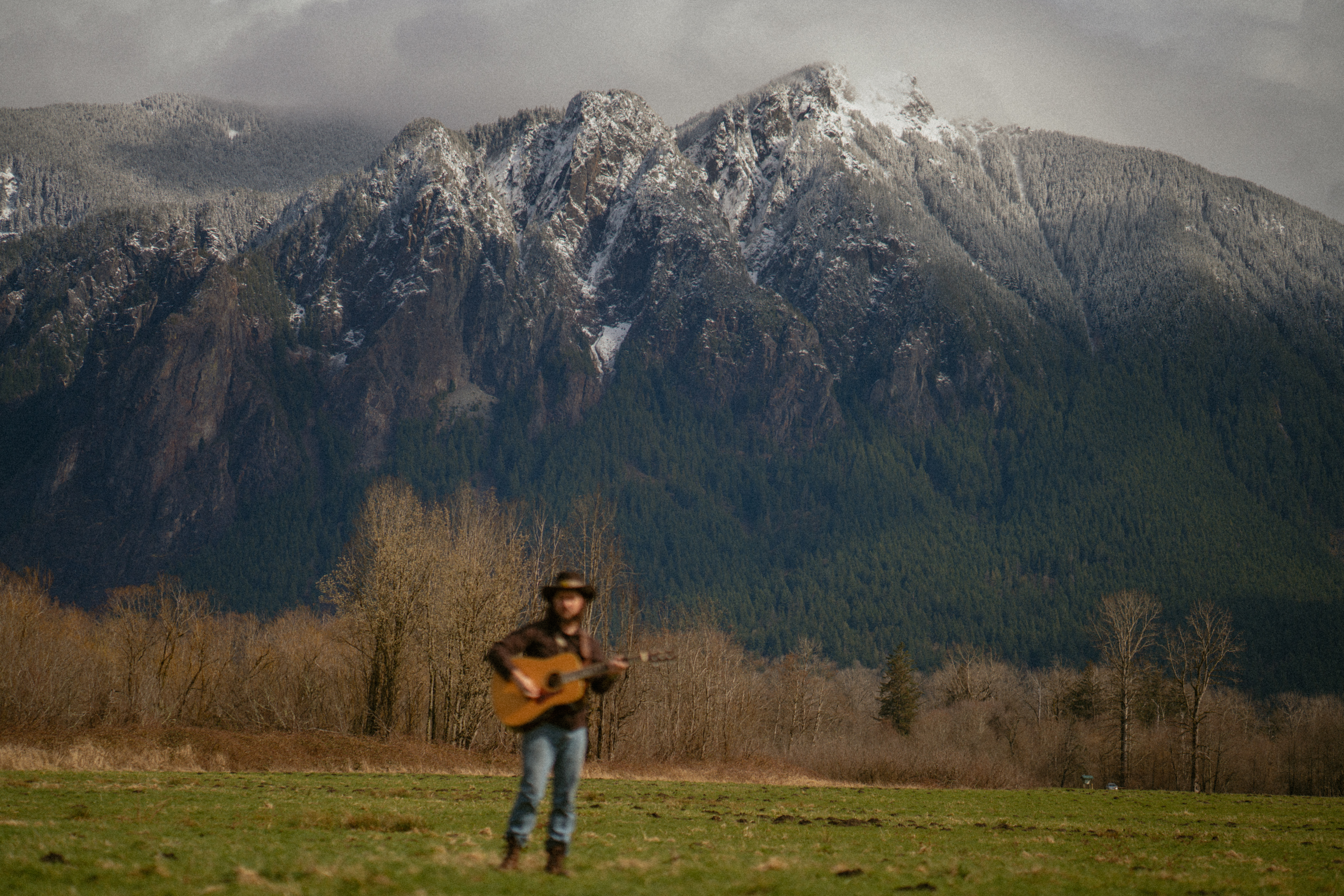 Country musician plays guitar in front of Mt. Si in Washington State